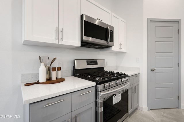 kitchen with light stone countertops, white cabinetry, appliances with stainless steel finishes, and gray cabinetry