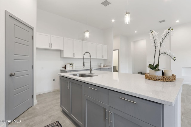 kitchen featuring decorative light fixtures, visible vents, gray cabinetry, white cabinets, and a sink