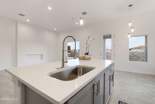 kitchen featuring a center island with sink, visible vents, pendant lighting, and a sink