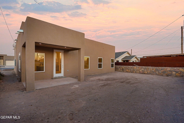 rear view of property featuring a patio, fence, and stucco siding