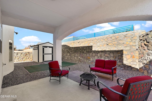 view of patio / terrace with an outdoor living space with a fire pit, a fenced backyard, an outdoor structure, and a shed