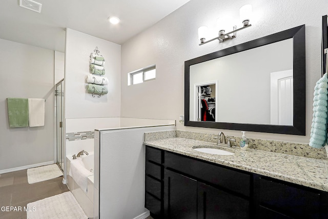 bathroom with a garden tub, a shower stall, a spacious closet, and visible vents