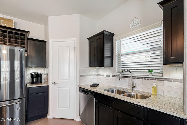 kitchen featuring stainless steel appliances, light tile patterned flooring, light stone countertops, and sink