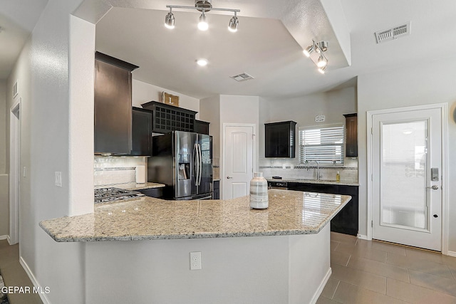 kitchen with visible vents, a peninsula, light stone countertops, stainless steel appliances, and a sink