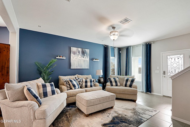 living area with ceiling fan, tile patterned flooring, visible vents, and baseboards