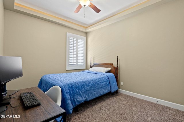 carpeted bedroom featuring a tray ceiling and ceiling fan