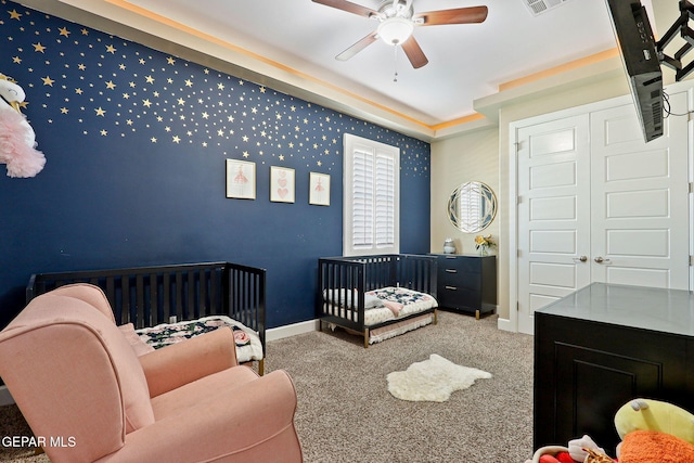 bedroom with a nursery area, carpet floors, and ceiling fan