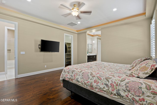 bedroom featuring dark wood-type flooring, ensuite bath, a spacious closet, and ceiling fan