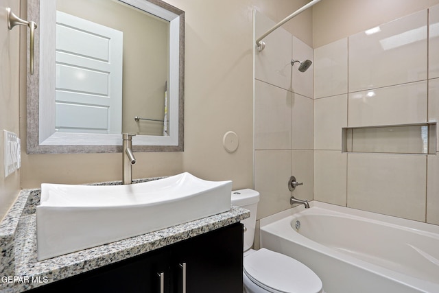 full bathroom featuring tiled shower / bath, vanity, and toilet