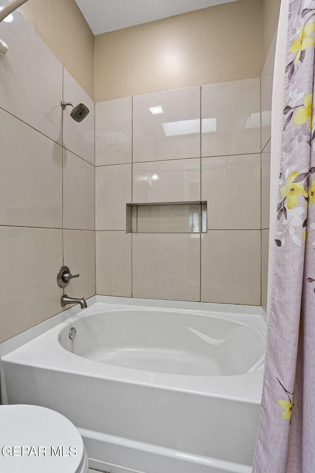 bathroom featuring tile walls, toilet, and shower / bath combo with shower curtain