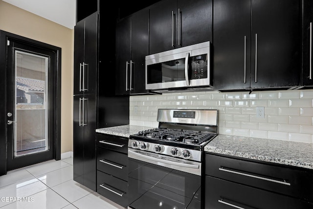 kitchen with light tile patterned flooring, stainless steel appliances, light stone countertops, and decorative backsplash