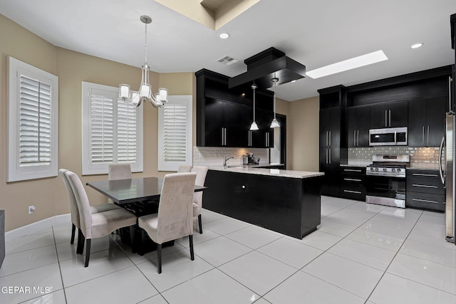 kitchen featuring light tile patterned flooring, appliances with stainless steel finishes, a chandelier, and hanging light fixtures