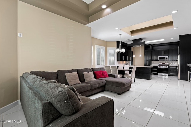 tiled living room featuring a notable chandelier and a tray ceiling