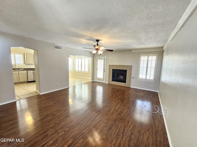 unfurnished living room featuring sink, a textured ceiling, a fireplace, and light hardwood / wood-style floors