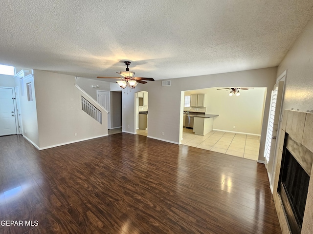 unfurnished living room with ceiling fan, light hardwood / wood-style floors, and a textured ceiling