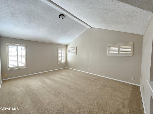 carpeted spare room with vaulted ceiling and a textured ceiling