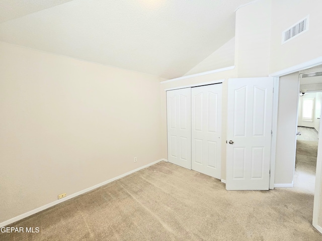 unfurnished bedroom with light carpet, high vaulted ceiling, and a closet