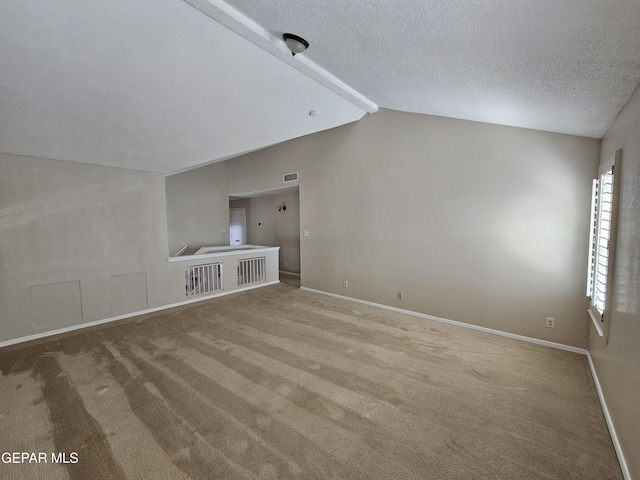 unfurnished living room with lofted ceiling with beams, a textured ceiling, and carpet flooring