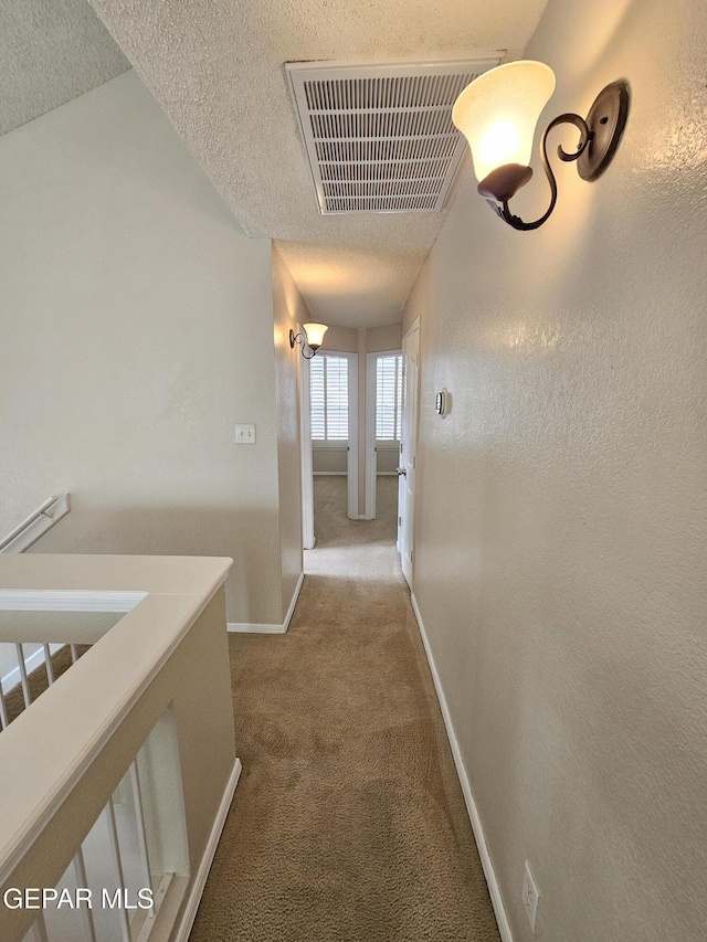 hallway with carpet flooring and a textured ceiling