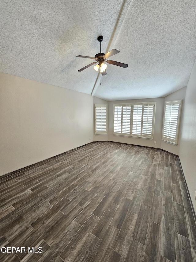 spare room featuring dark wood-type flooring, vaulted ceiling, and a wealth of natural light