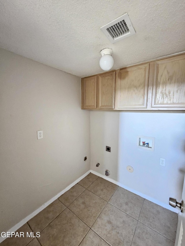 washroom with cabinets, a textured ceiling, light tile patterned floors, washer hookup, and hookup for a gas dryer