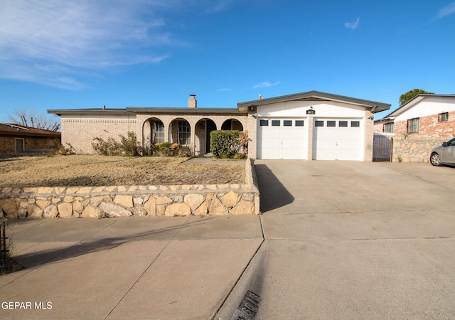 single story home featuring a garage, driveway, brick siding, and a chimney