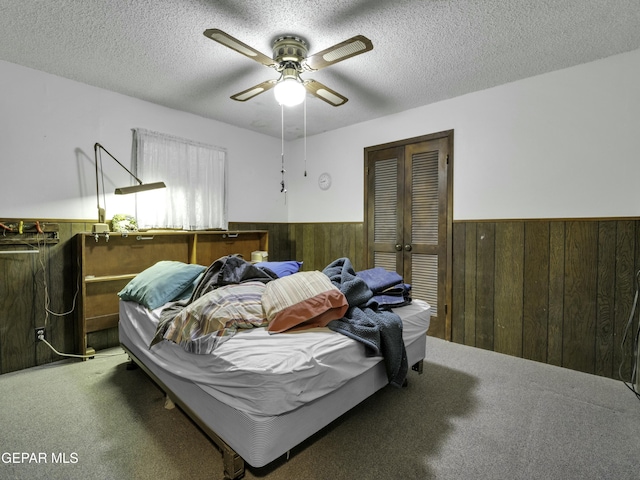 bedroom with a closet, wooden walls, carpet, and a textured ceiling