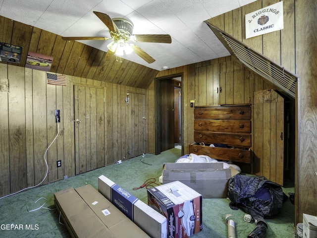 additional living space with ceiling fan, wooden walls, vaulted ceiling, and carpet