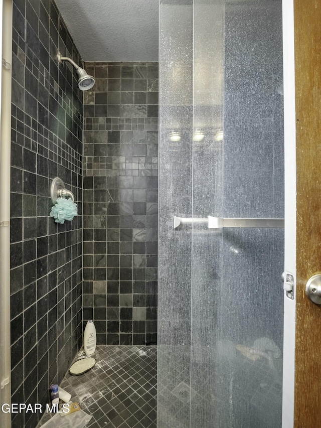 bathroom with tiled shower and a textured ceiling