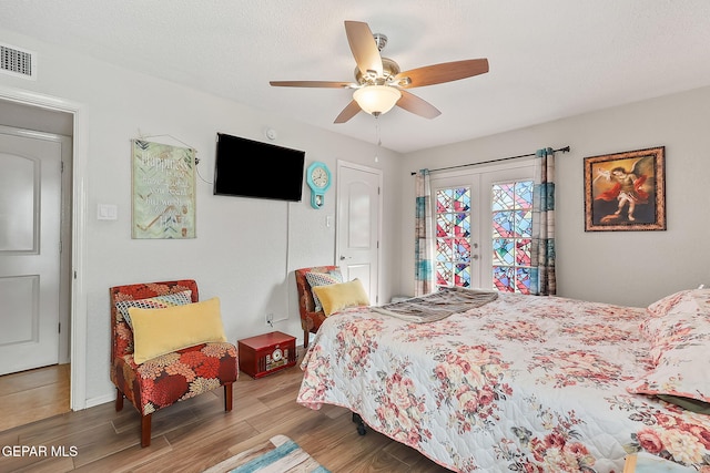 bedroom with wood-type flooring, access to outside, ceiling fan, a textured ceiling, and french doors