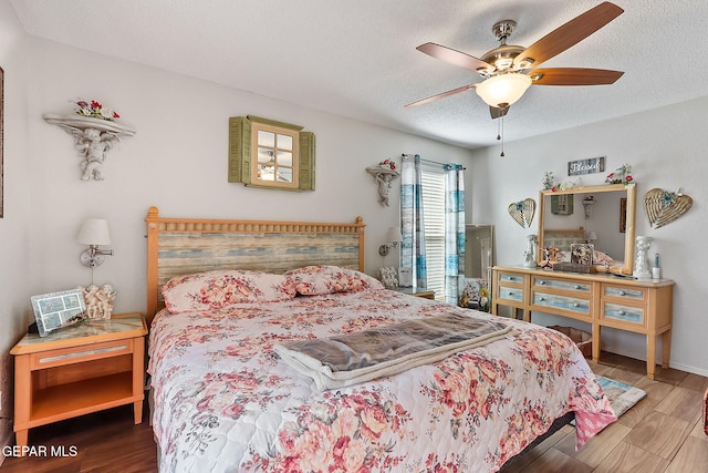 bedroom featuring ceiling fan, hardwood / wood-style floors, and a textured ceiling