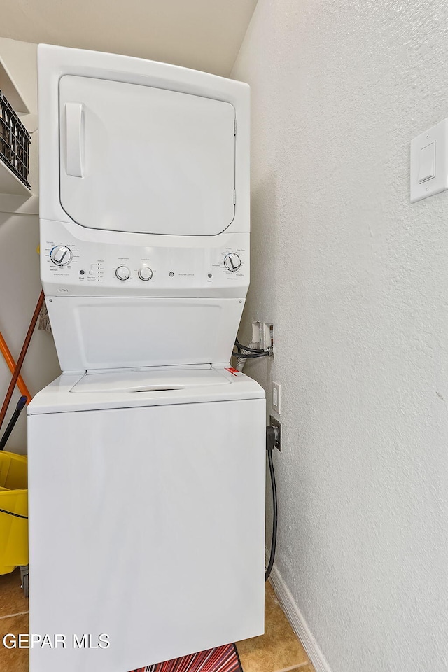 laundry room featuring tile patterned flooring and stacked washer / drying machine