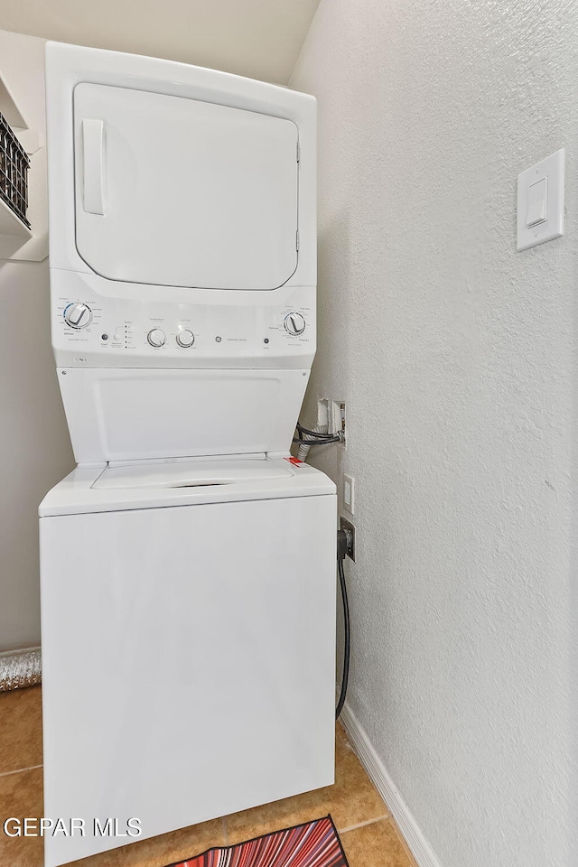 clothes washing area with light tile patterned floors and stacked washer and clothes dryer