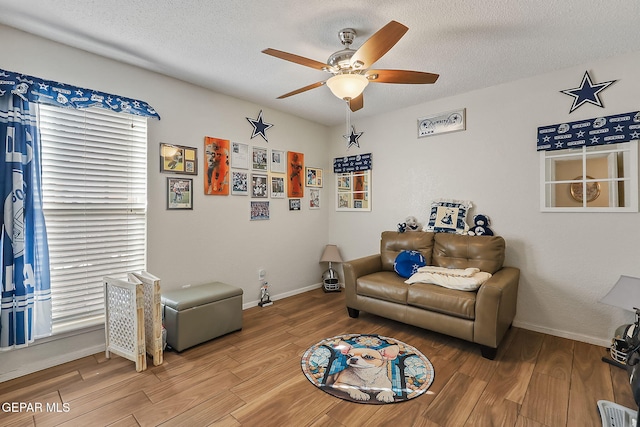 living room with hardwood / wood-style flooring, ceiling fan, and a textured ceiling