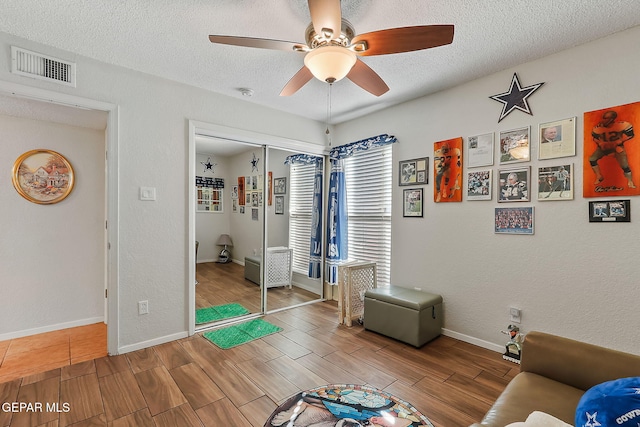 sitting room featuring hardwood / wood-style flooring, ceiling fan, and a textured ceiling