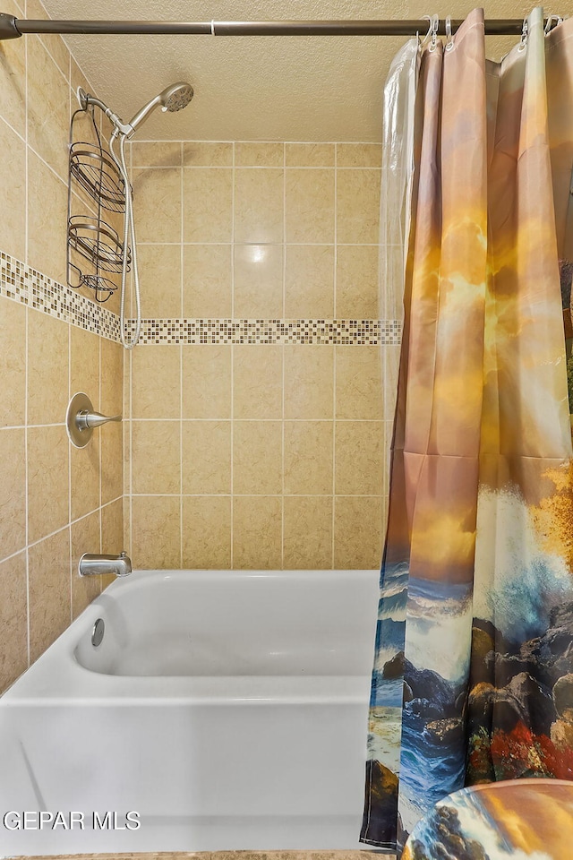 bathroom with shower / bath combo and a textured ceiling