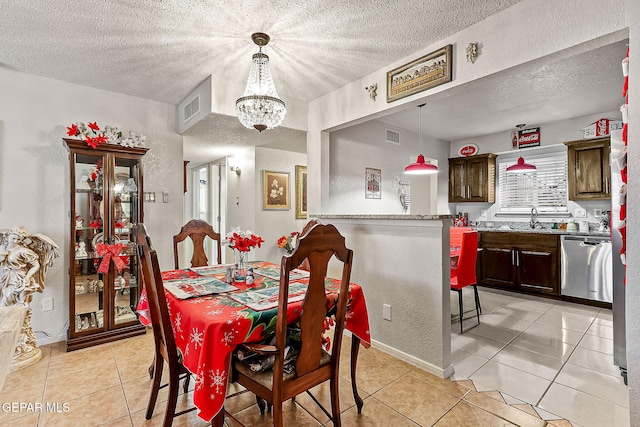 dining space featuring an inviting chandelier, sink, a textured ceiling, and light tile patterned flooring