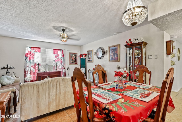 dining space featuring light tile patterned flooring, ceiling fan with notable chandelier, and a textured ceiling