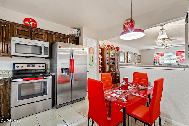 kitchen with hanging light fixtures, dark brown cabinets, light tile patterned flooring, and appliances with stainless steel finishes