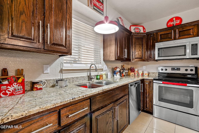 kitchen with sink, appliances with stainless steel finishes, dark brown cabinets, light stone counters, and light tile patterned flooring