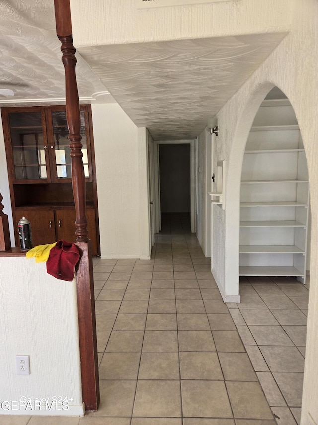 hallway with light tile patterned floors and built in shelves