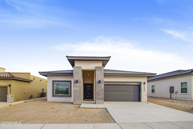 prairie-style home with cooling unit and a garage