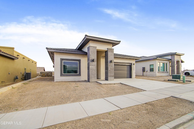 prairie-style home with a garage and central AC unit