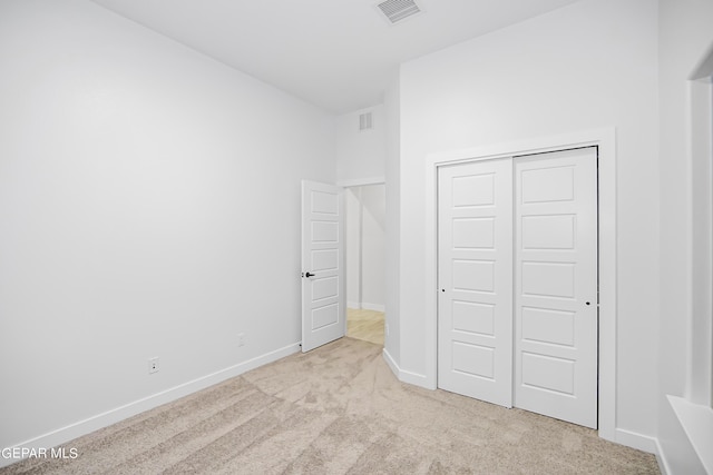 unfurnished bedroom with light colored carpet and a closet