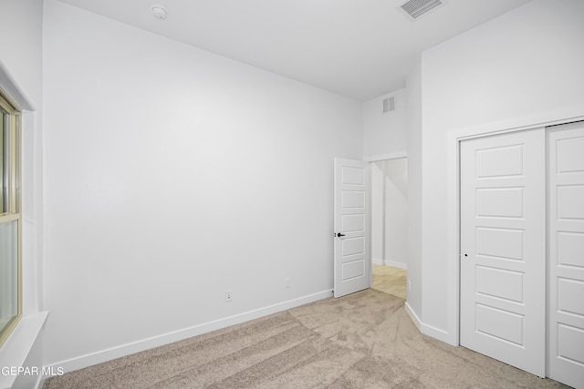 unfurnished bedroom with light carpet and a closet