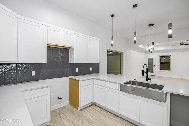 kitchen featuring white cabinetry, hanging light fixtures, decorative backsplash, and sink