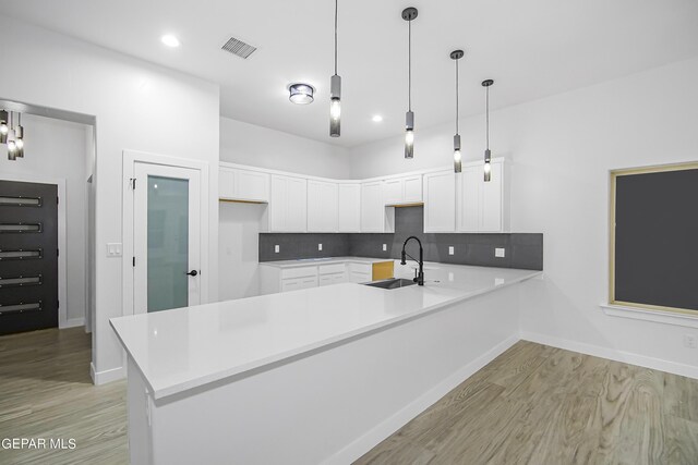 kitchen with sink, hanging light fixtures, and white cabinets