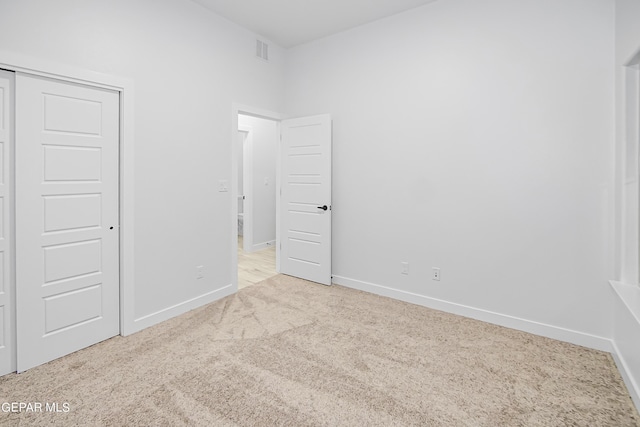 unfurnished bedroom with light carpet and a closet