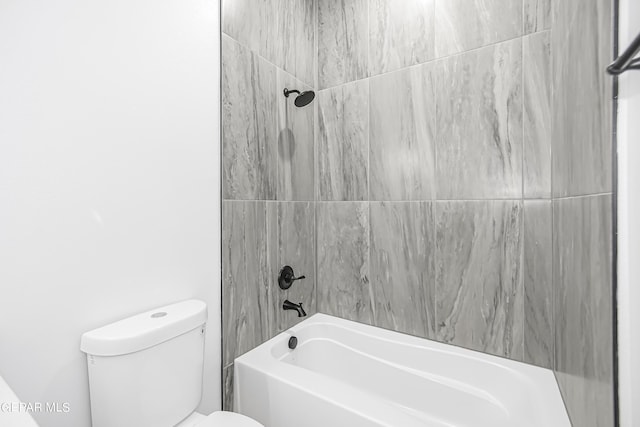 bathroom featuring tiled shower / bath combo and toilet