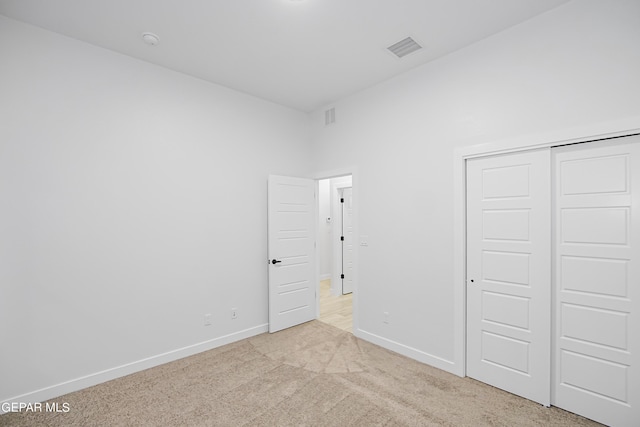 unfurnished bedroom with light colored carpet and a closet